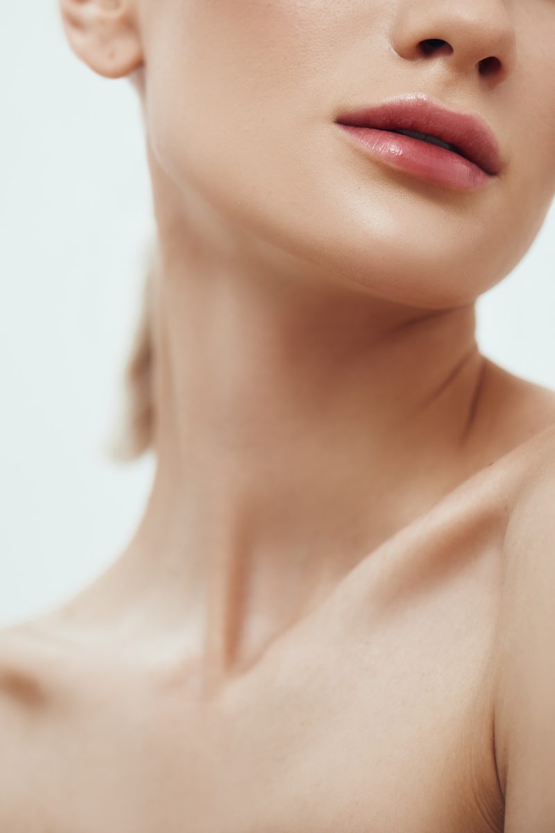 Tenderness and beauty. Cropped photo of attractive young woman with naked shoulder standing against grey background